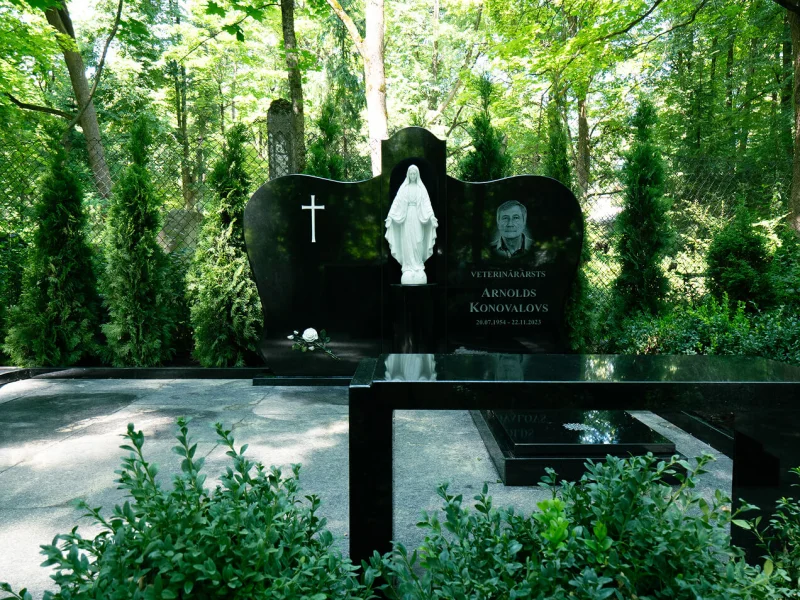 Divdaļīgs kapu piemineklis ar centrālo daļu skulptūrai.