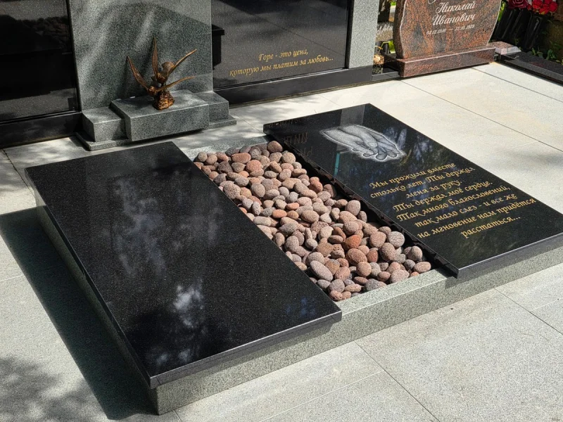 Slēgtās kapu plāksnes uz slēgtajām granīta grīdām kapavietas laukumā.